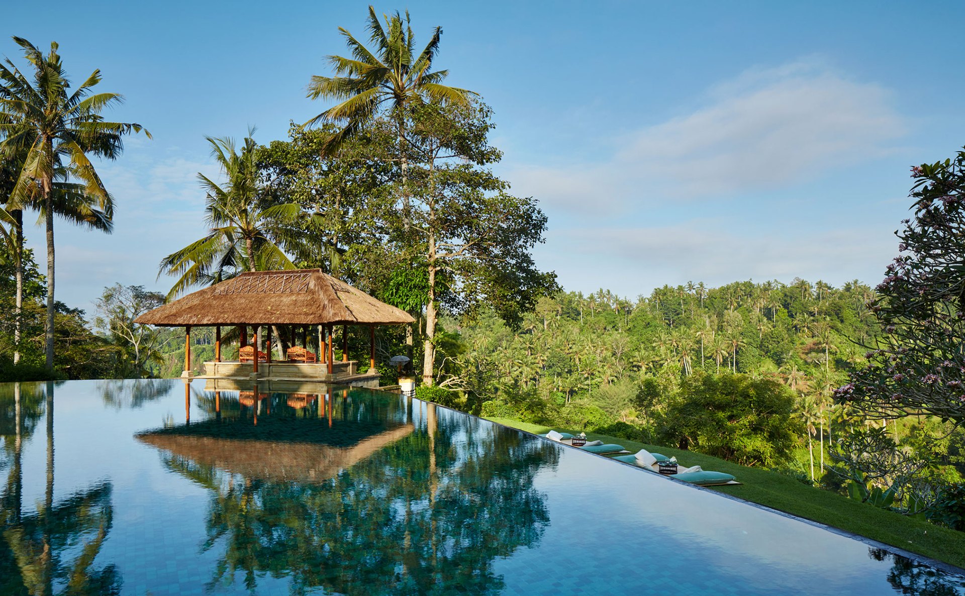 The infinity pool and thatched pavilion of Amandari above the Ayung valley, under a clear sky