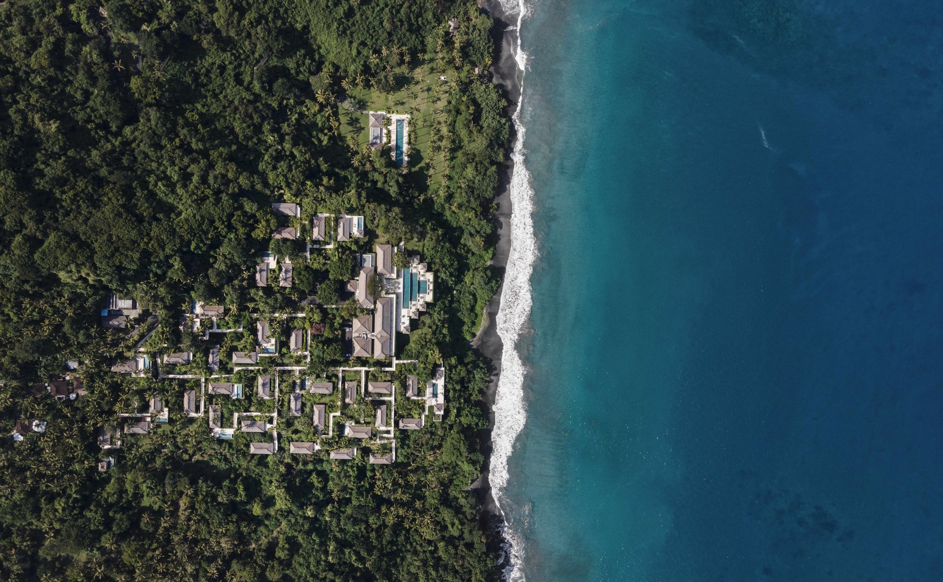 Amankila’s villas in the forest above a black-sand beach and the sea, from the air